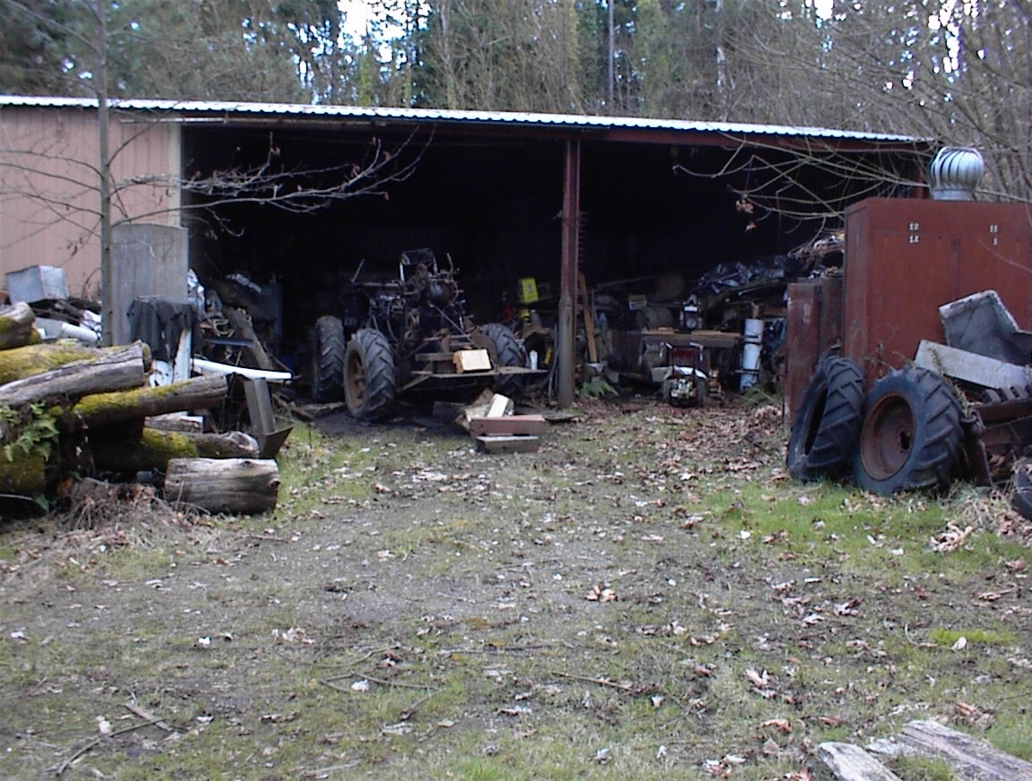 Open shed with vintage tractor and farm equipment inside