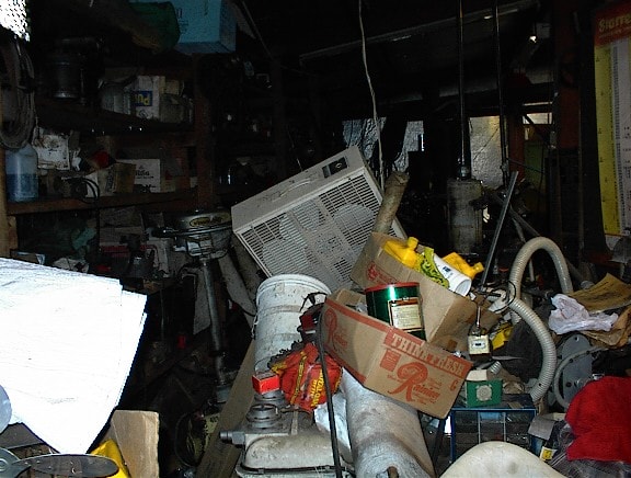 Cluttered shed interior packed with tools, boxes and miscellaneous items